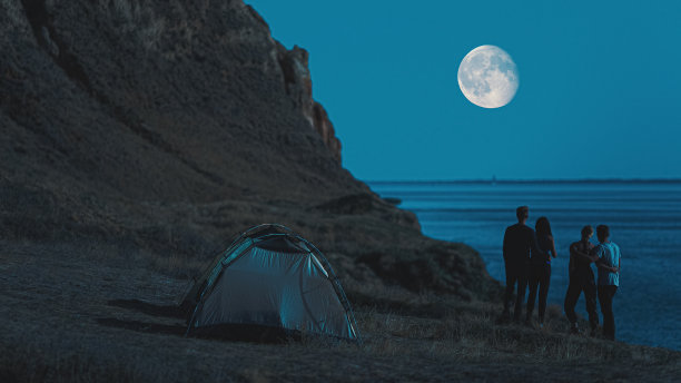 在夜景背景中，徒步旅行者站在露营帐篷附近图片下载