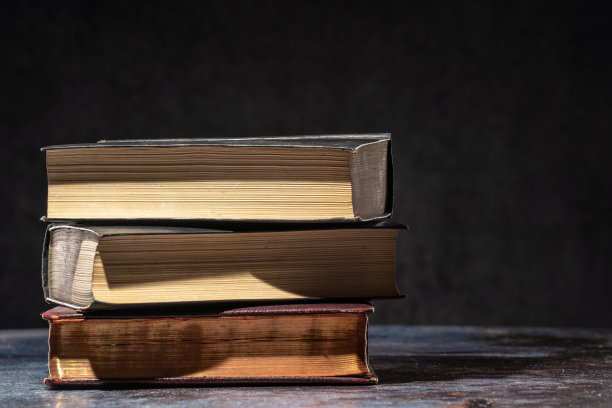 黑暗背景上的桌子上放着一堆旧书图片下载