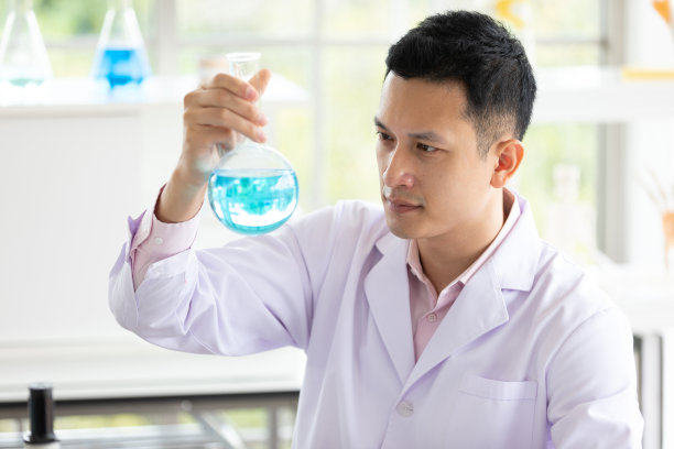 一个年轻的科学家拿着科学玻璃烧瓶和蓝色液体在一个实验室图片下载