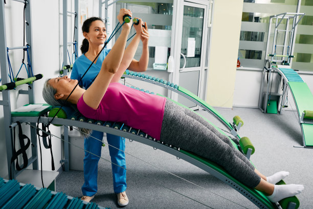 理疗师协助一名女患者进行脊柱和背部康复，并在康复室使用专用康复训练机进行恢复图片下载