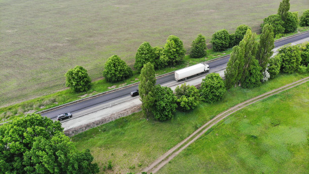 天线。运输物流的背景。卡车在田地间的高速公路上行驶。从无人机上俯瞰。图片下载