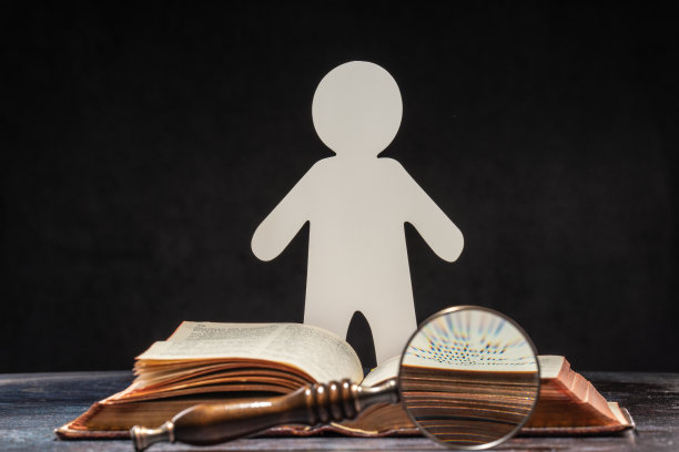 一个用纸雕刻的人站在一本打开的书前。学习和知识的概念图片下载