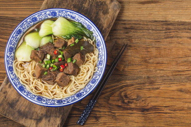 麻辣红汤牛肉面放在木桌上的碗里图片下载