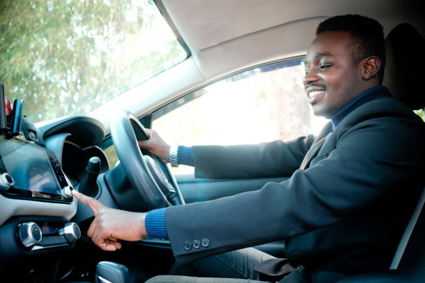 非洲人在黑色西装坐在方向盘后面微笑和幸福图片下载
