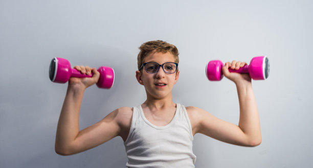 戴眼镜的金发男孩微笑着举着粉色的哑铃图片下载