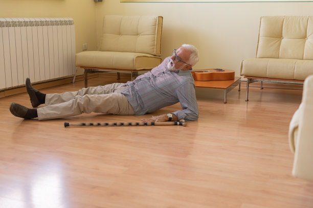 一名拄着拐杖的残疾退休人员跌倒在客厅的地板上。图片下载