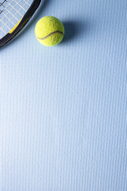 在运动垫子的背景上放一个网球拍和一个网球。图片下载