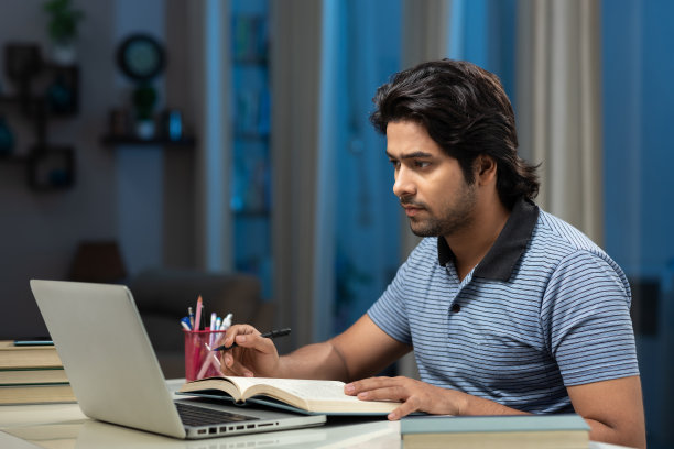 一个年轻男子大学生使用笔记本电脑在家学习的肖像:-库存照片图片下载