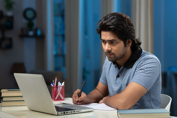 一个年轻男子大学生使用笔记本电脑在家学习的肖像:-库存照片图片下载