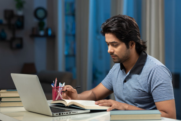 一个年轻男子大学生使用笔记本电脑在家学习的肖像:-库存照片图片下载