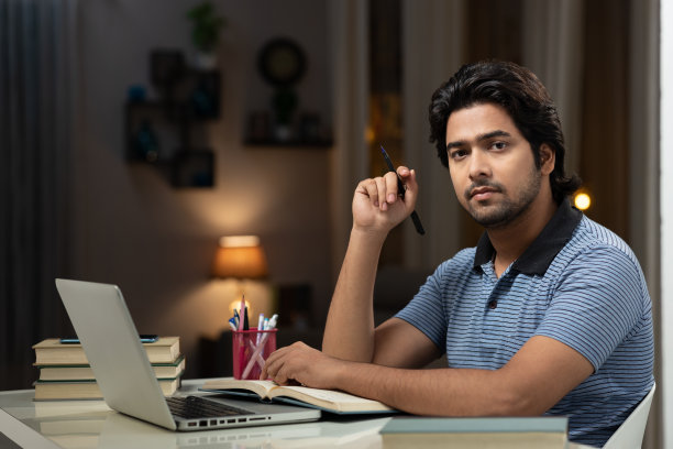 一个年轻男子大学生使用笔记本电脑在家学习的肖像:-库存照片图片下载