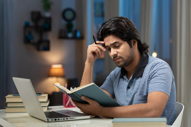 一个年轻男子大学生使用笔记本电脑在家学习的肖像:-库存照片图片下载