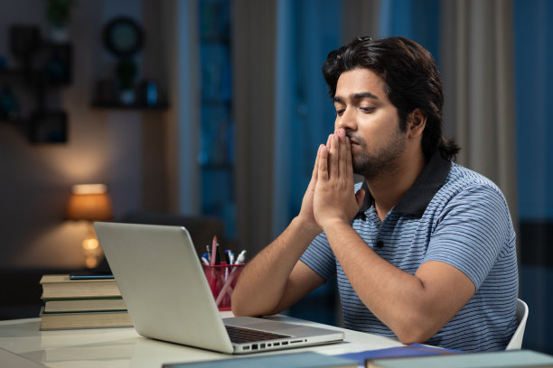 一个年轻男子大学生使用笔记本电脑在家学习的肖像:-库存照片图片下载