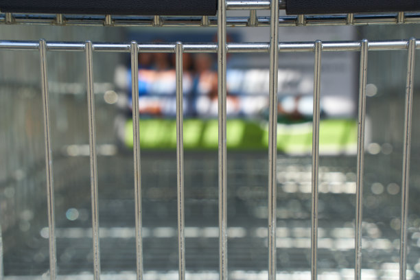 购物车的铁丝篮。食品店的广告挂在上面(模糊的)。特写镜头。图片下载