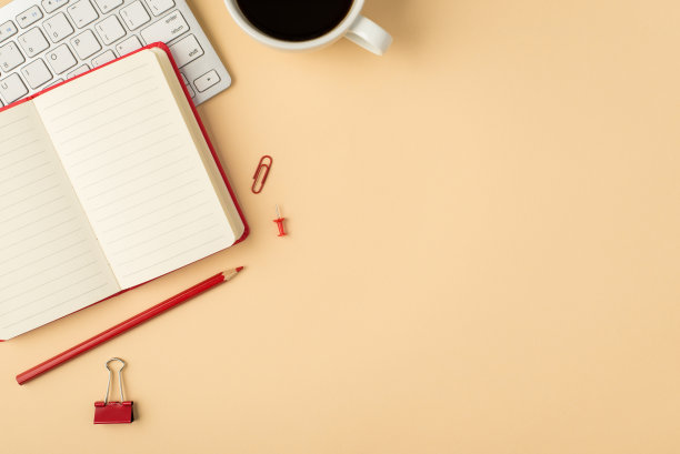 俯视图照片白色键盘文具打开红色日记本铅笔活页夹别针和咖啡杯上孤立的米色背景与copyspace图片下载