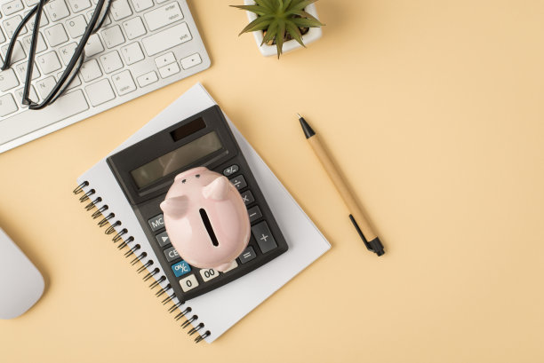 俯视图照片白色键盘，鼠标眼镜，花盆，钢笔，储蓄罐，计算器和抄写本上孤立的米色背景与抄写空间图片下载