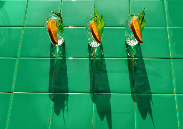 清爽的饮料在水晶玻璃杯与树叶橙色片绿色瓷砖的背景阴影。甜冷天然鸡尾酒图片下载