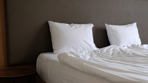 卧室的近距离片段与空床头柜，阅读灯和USB插座在现代室内设计的家庭或酒店。柔软的枕头和毯子，时尚舒适的家具。图片下载