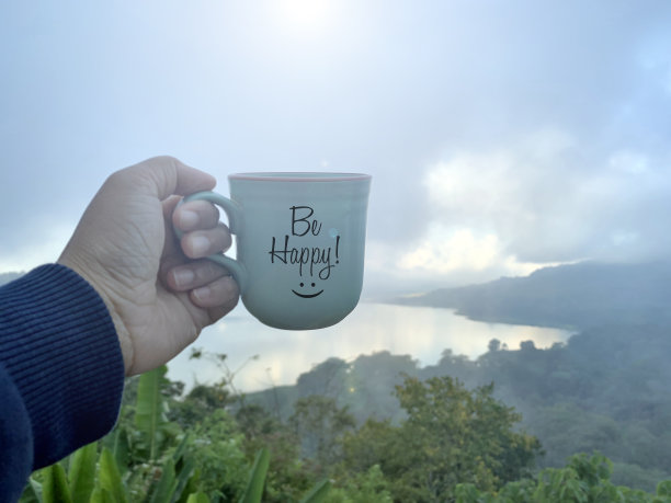 手捧一杯茶或咖啡，与文字一起快乐，以蓝山湖自然为背景。图片下载