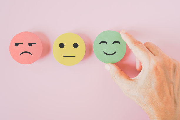 手选绿色纸剪快乐笑脸在粉色背景上进行心理健康评估，积极思考，世界心理卫生日，客户点评，体验，满意度调查理念图片下载