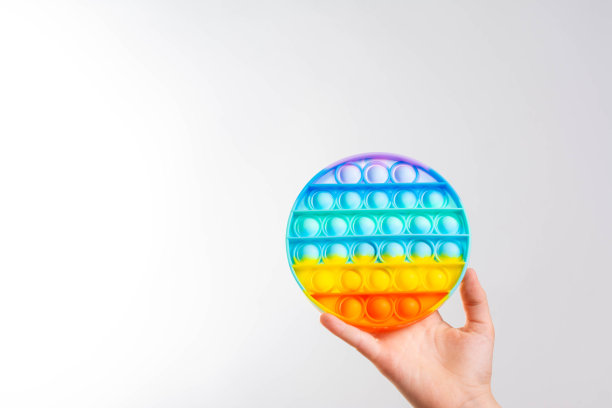 彩色的抗压力感官玩具烦躁推弹它在孩子的手中孤立的灰色背景。时尚流行的硅胶彩色抗应力弹它的圆形玩具。关闭了。本空间图片下载