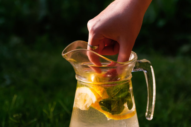 将草莓与柠檬片和薄荷放在天然的深绿色背景的柠檬水玻璃罐中。一壶寒冷的夏日阳光鸡尾酒或户外潘趣酒。副本的空间。的焦点图片下载