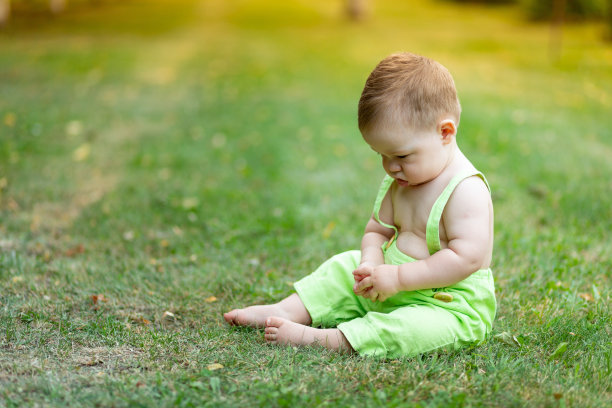 夏天，一个小男孩在绿色的草坪上伤心欲泣，低头看了看，这是一个发短信的地方图片下载