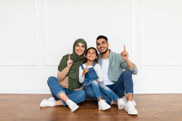 快乐的男人、女人和女孩在家里用手指指向上方图片下载