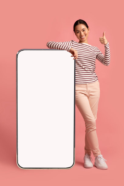 开朗的韩国女士靠在大空白智能手机上，竖起大拇指图片下载