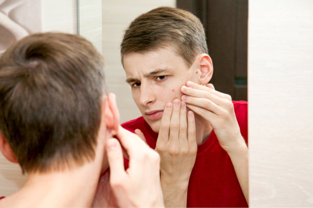 近距离的年轻有吸引力的男人有问题的皮肤和疤痕痤疮看在浴室的镜子图片下载