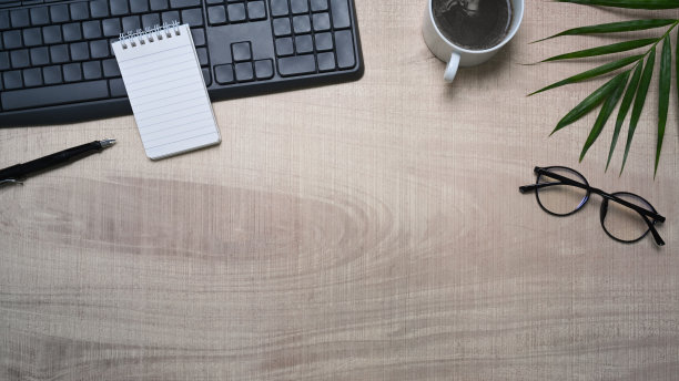 上面的视图眼镜，咖啡杯，键盘和笔记本在木桌上。图片下载