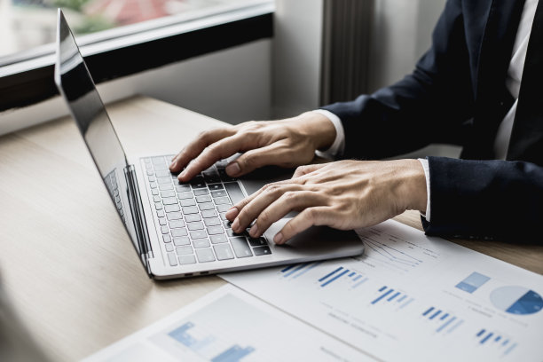 特写照片的男人在一个笔记本电脑键盘上打字，商务人士打字聊天与商业伙伴通过在线信使。在通信中使用技术的概念。图片下载