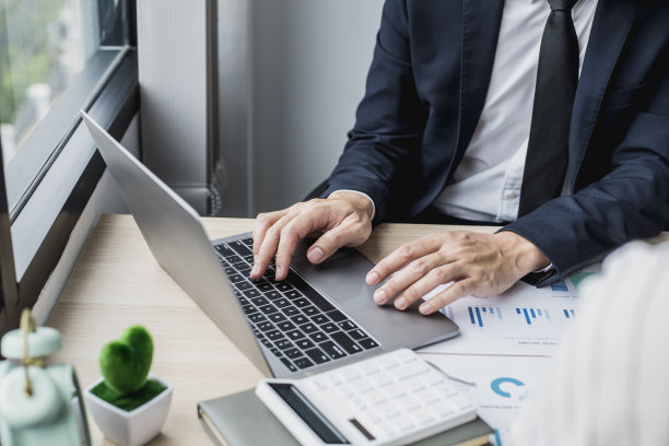 西装革履的他正在用笔记本电脑工作，他是一名年轻的商人，创立了一家初创公司，他正在通过笔记本电脑上的一个在线messenger与他的伴侣发送短信。图片下载