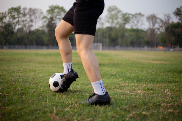 运动和娱乐概念一名男性足球运动员穿着黑色的t恤和裤子在草地上练习踢球。图片下载