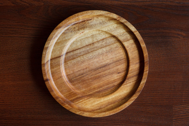 深色木桌上一个纹理优美的空木盘。图片下载
