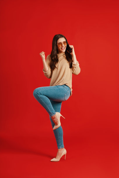 全身快乐的年轻女子在休闲服装谈论电话和欢呼图片下载