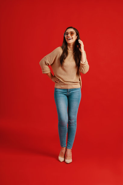 全身美丽的年轻女子在休闲服装微笑和电话交谈图片下载