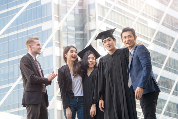 人们怀着快乐和感恩的心情，带着毕业礼服和毕业帽，与父母和朋友站在一起，在户外现代城市空间里欢快地打招呼。图片下载