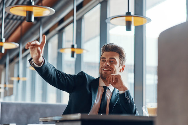 英俊的年轻微笑的男人在全套西装保持手臂抬起图片下载