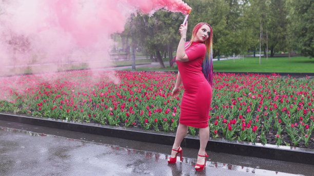 一个女孩带着彩虹辫，穿着红裙子摆姿势图片下载