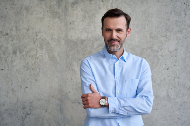 成功的中年商人靠在水泥墙上图片下载