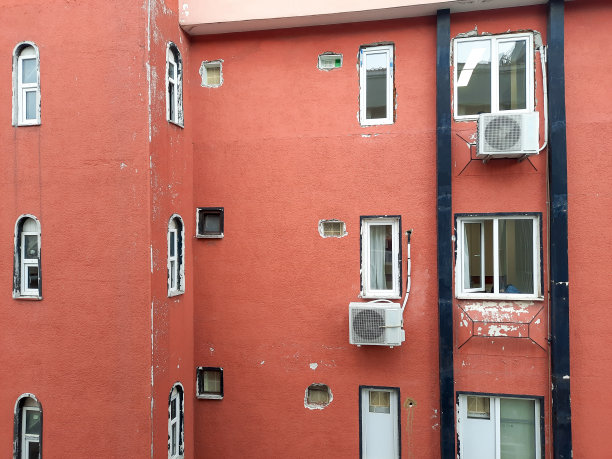 旧的橘黄色公寓楼，有很多破损的白色窗户图片下载