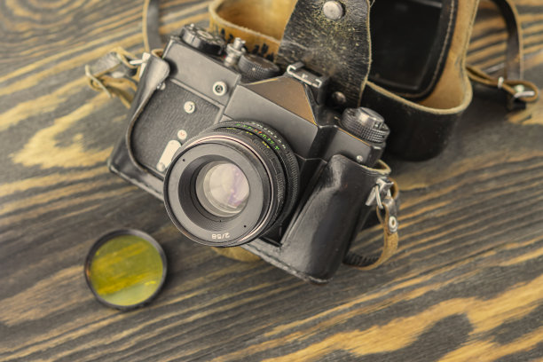 复古胶片相机，老带盖相机带镜头和偏光黄色滤光木桌背景，复古色调。图片下载