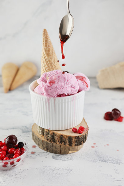 白色花岗岩上，勺子舀起的华夫筒冰淇淋和糖浆图片下载