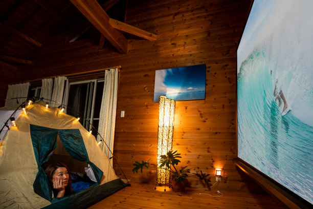 一个女人在家里露营，在室内看大放映机屏幕上的电影图片下载