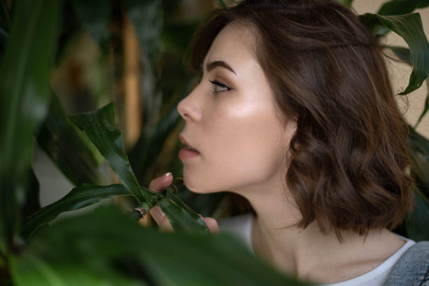 棕色头发的年轻女孩在绿叶中摆姿势图片下载