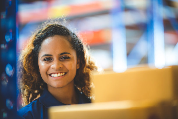 一个年轻的妇女女士女孩是工作在仓库仓库穿着蓝色t- shrt制服检查库存，美国非洲棕色卷发雇员在工厂工作，赋权妇女，工作理念。肖像照片。图片下载