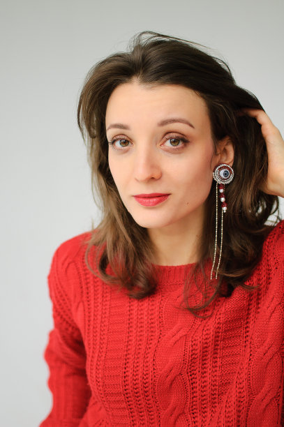 工作室肖像的年轻女子在红色针织毛衣和耳环在白色的背景图片下载