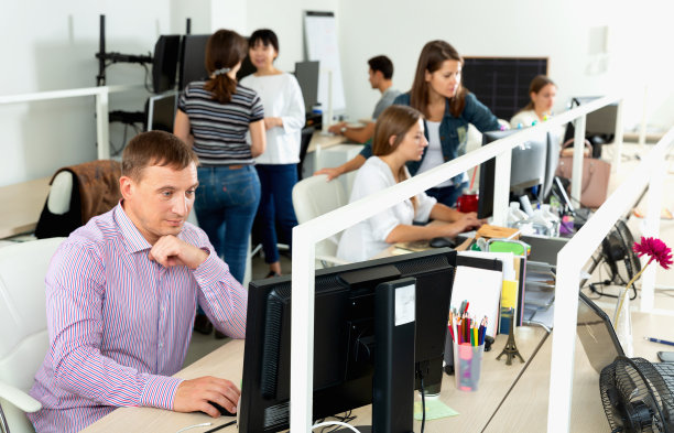 英俊的年轻人自信地在现代开放式办公室电脑上工作图片下载