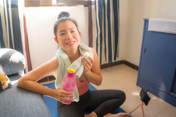 健康的生活方式肖像，年轻的快乐和美丽的亚洲中国妇女微笑出汗训练后，在瑜伽垫上锻炼，在她的手机在家里在线课程图片下载